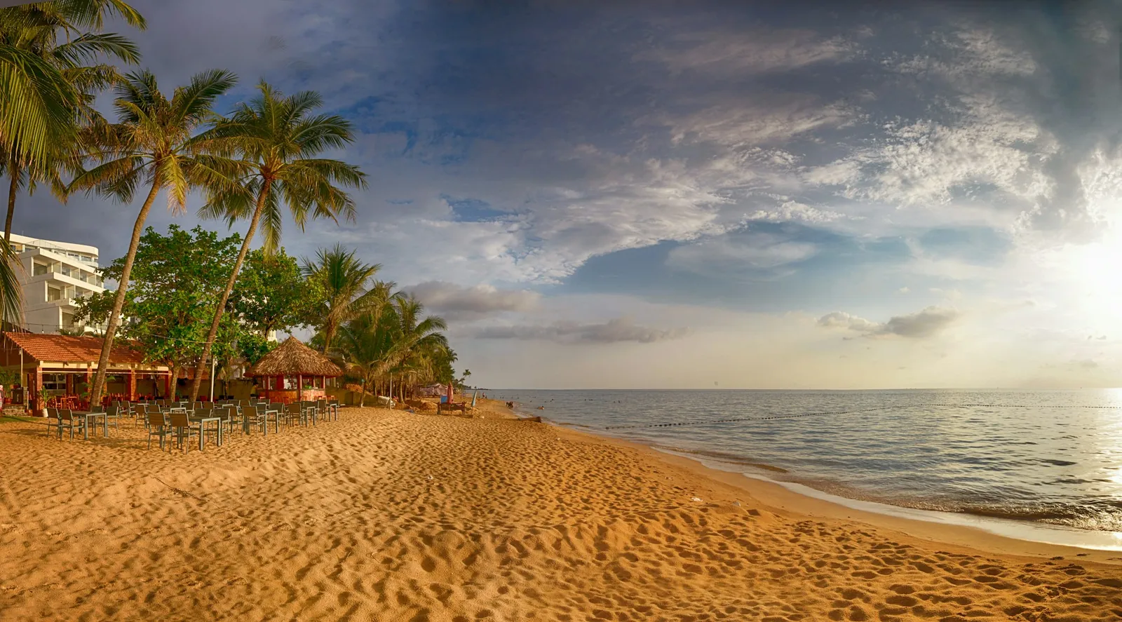 Hotell, strandrestaurang och palmer vid Long Beach på Phu Quoc i kvällsljus