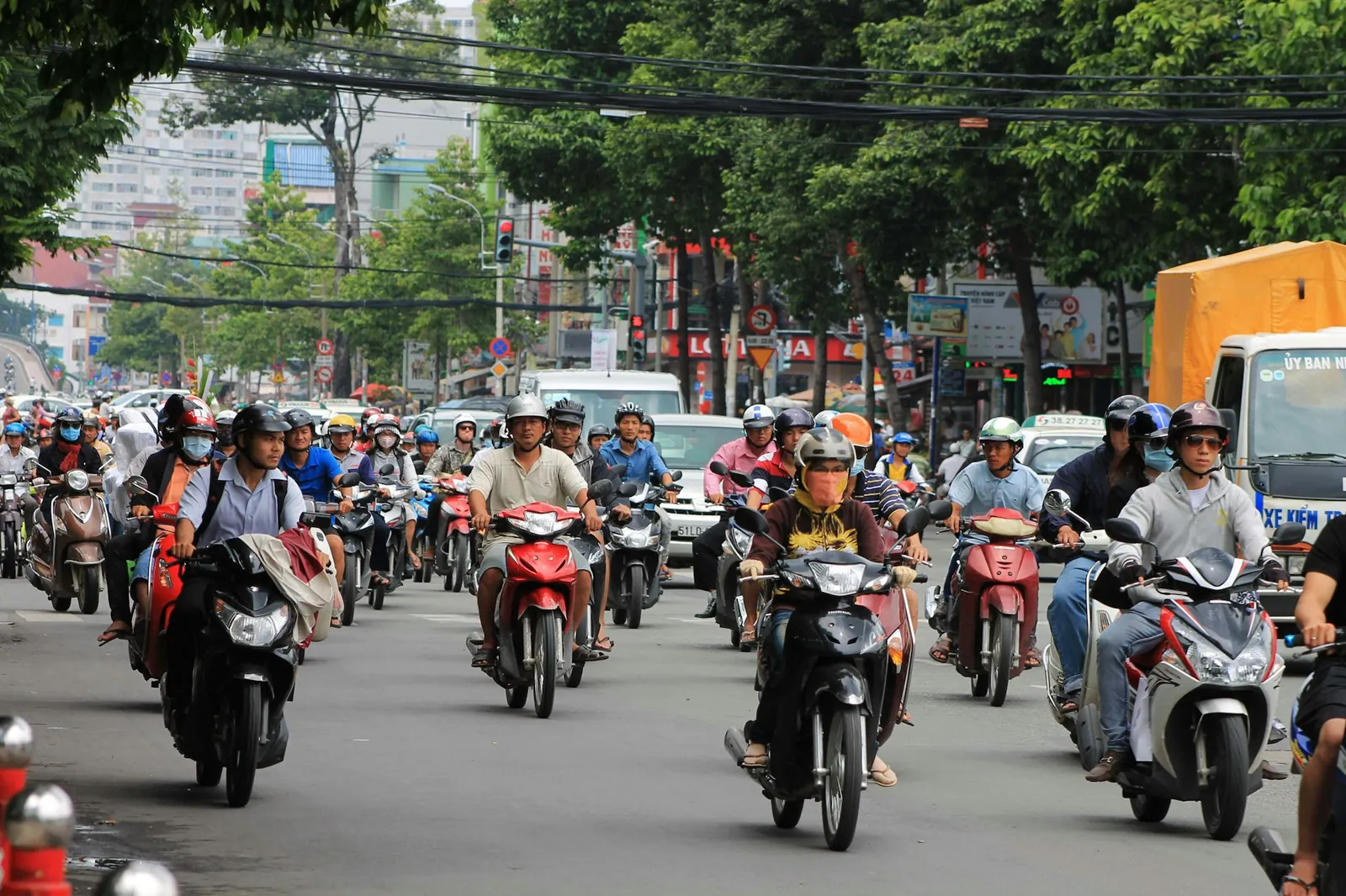 Tät mopedtrafik på en trädkantad gata i Ho Chi Minh-staden