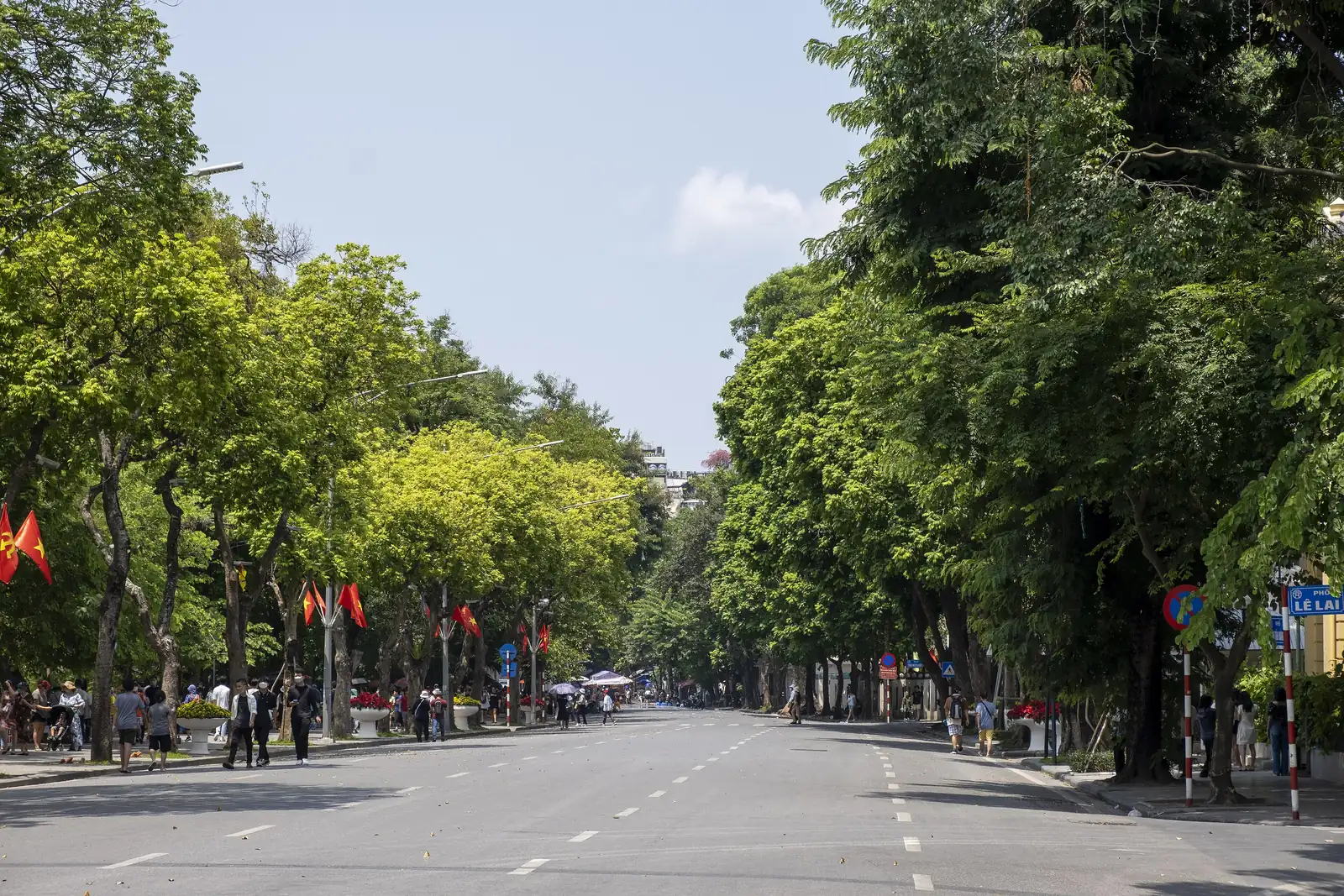 Lummig allé med vietnamesiska flaggor längs Dinh Tien Hoang-gatan vid Hoan Kiem-sjön i Hanoi