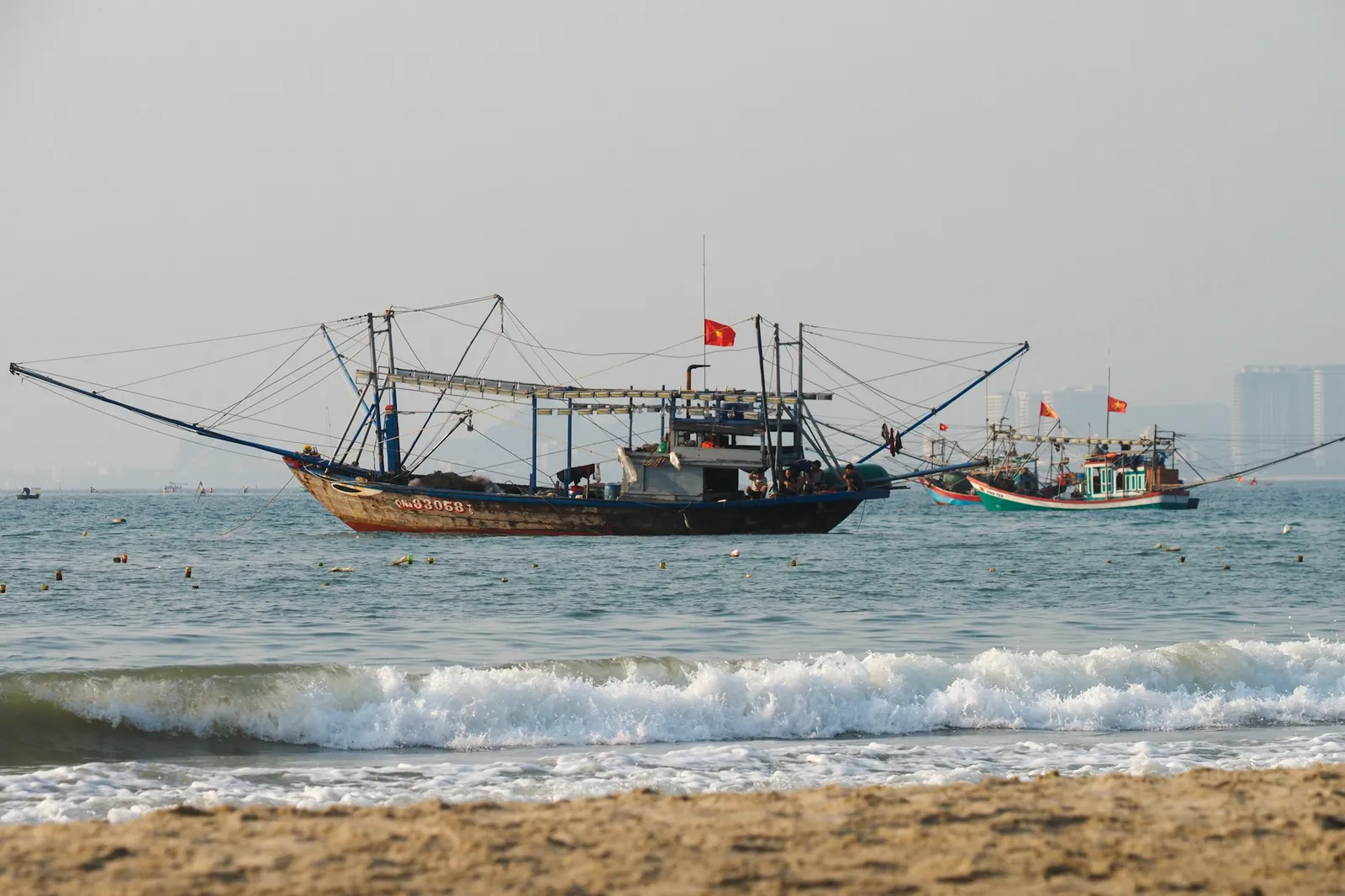 Fiskebåtar med vietnamesiska flaggor ankrade utanför stranden i Da Nang