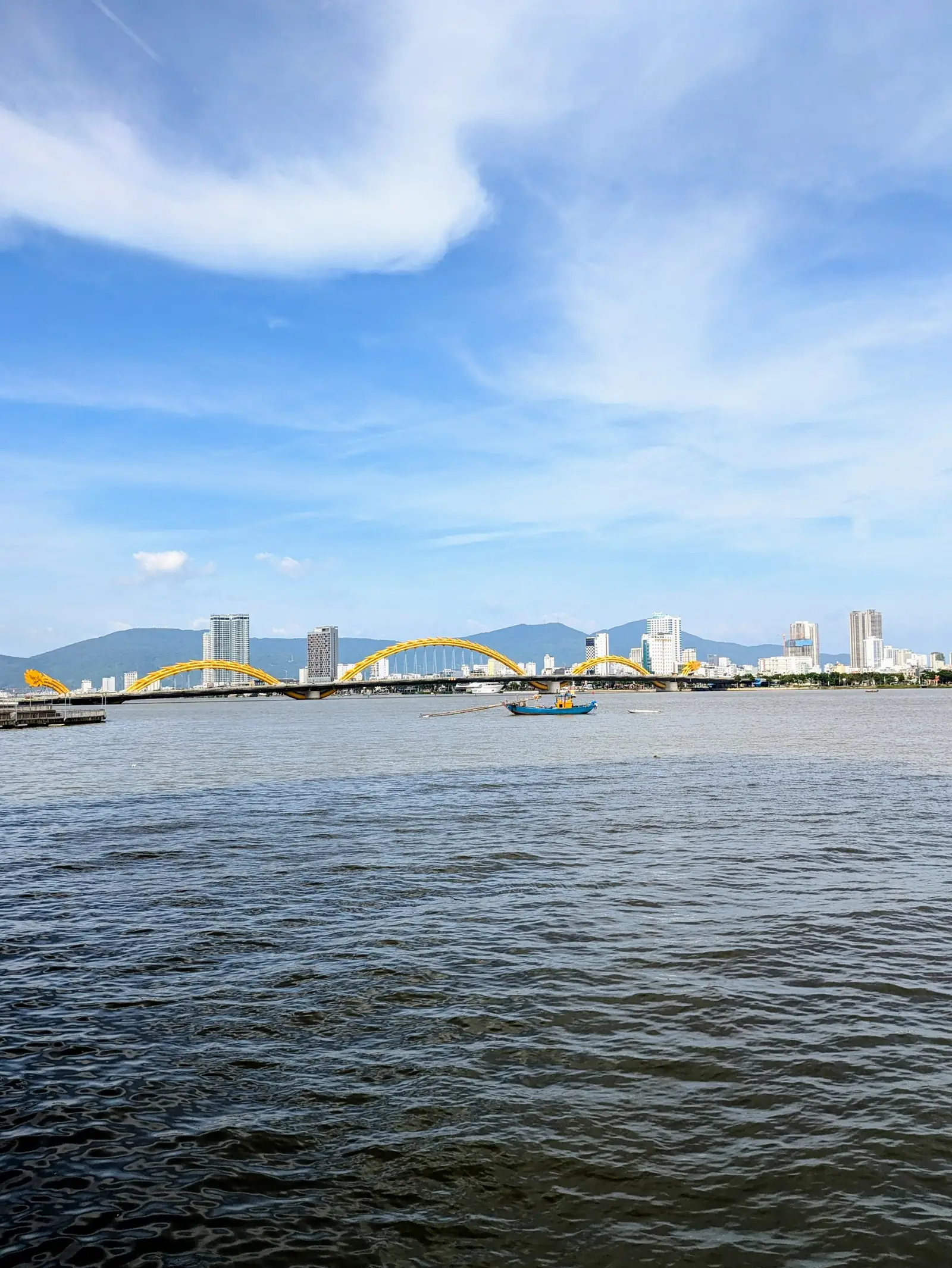 Drakbron (Dragon Bridge) över Hanfloden i Da Nang med staden och bergen i bakgrunden