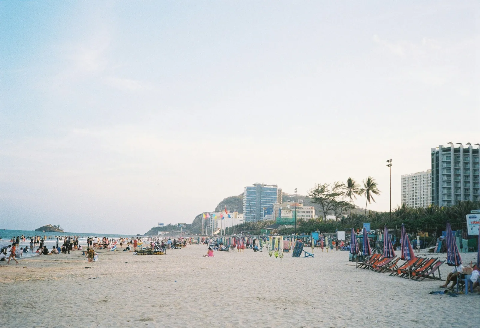 Stranden i Vung Tau med parasoller, badgäster och hotell längs strandpromenaden