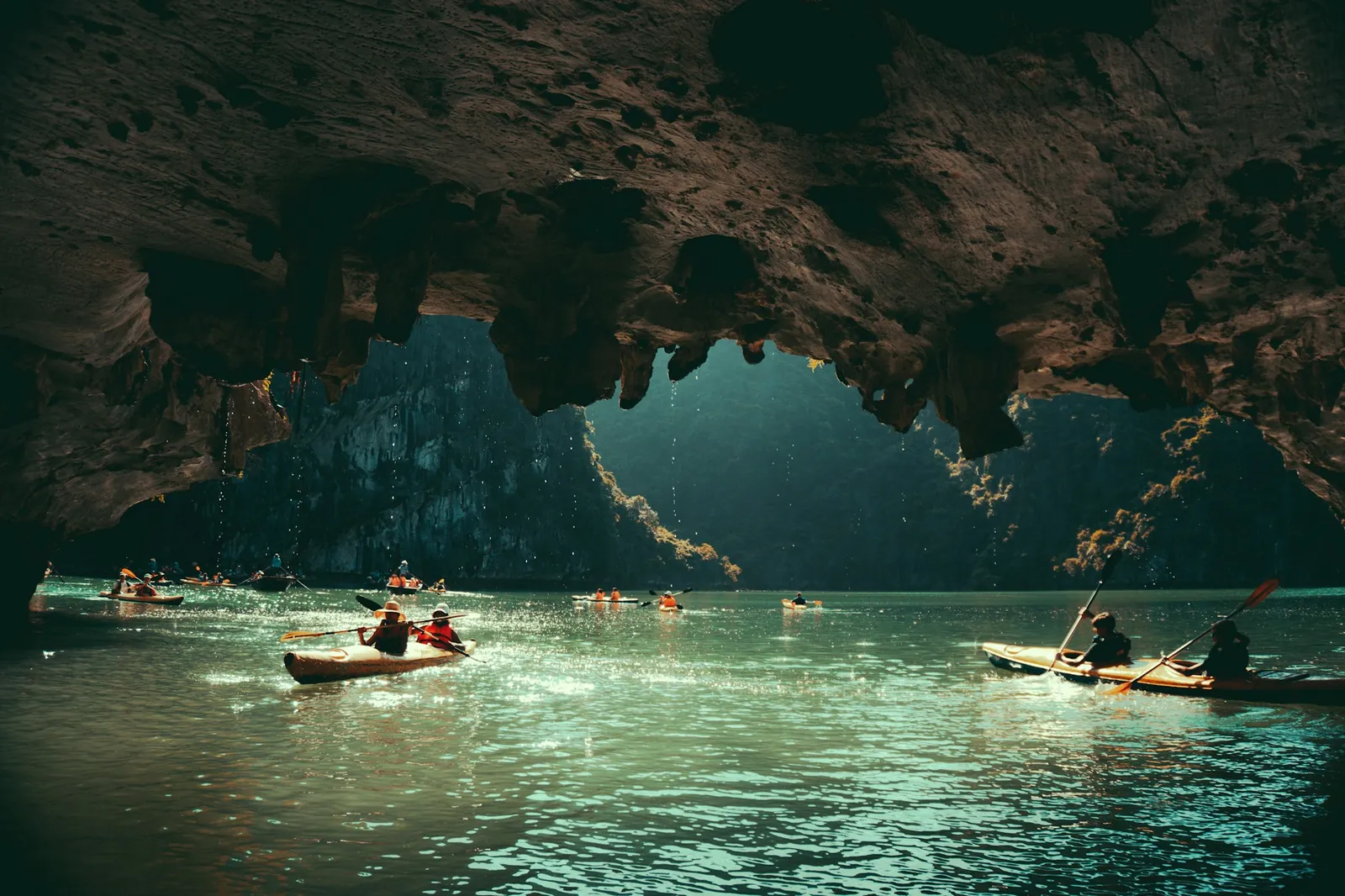 Kajakpaddlare i en grotta bland kalkstensklipporna i Ha Long-bukten
