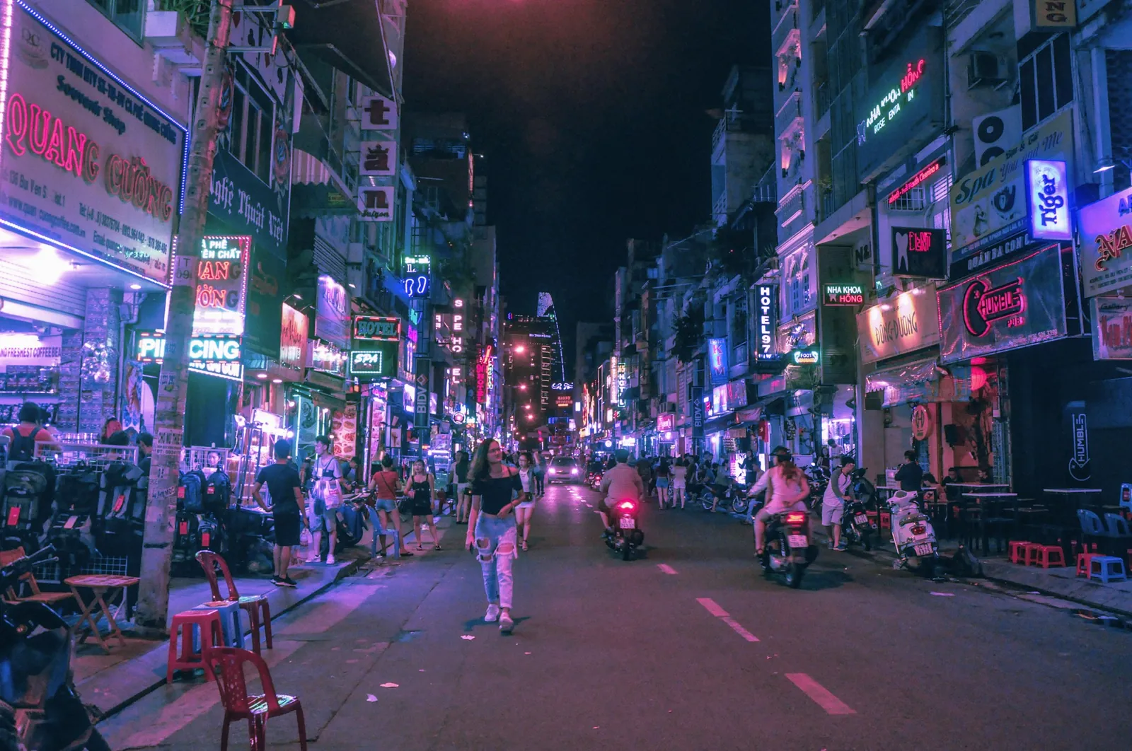 Gågatan Bui Vien i Ho Chi Minh-staden på kvällen med neonskyltar, barer och mopeder